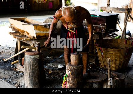 Thai oldman persone fabbro o metalaio che fanno antiche armature di ferro e metallo d'acciaio armi antiche in bottega di fabbro locale di Bang Rachan villaggio a Foto Stock