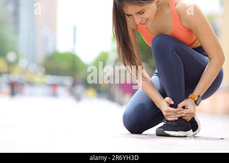 Runner che soffre mal di caviglia lamentarsi in strada Foto Stock