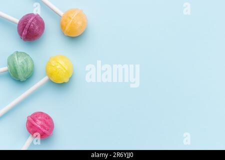 Lecca lecca colorata su sfondo blu. Piano di giacitura, vista dall'alto Foto Stock