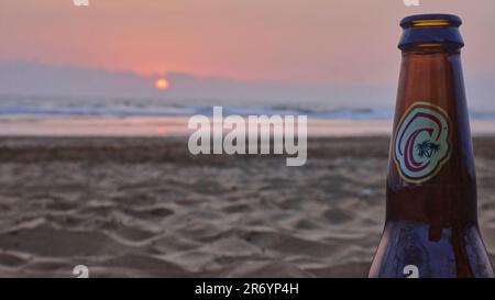 Casablanca, Marocco - 05 19 2016: Bottiglia di birra di Casablanca in piedi su una spiaggia di sabbia di fronte a un romantico tramonto sull'oceano atlantico. Foto Stock