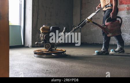 Lavoratore che esegue e lucidando il pavimento del banco di stesa per sabbia e cemento in cantiere Foto Stock