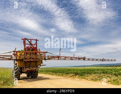 Trattore agricolo in movimento su strada agricola dopo l'irrorazione del campo Foto Stock