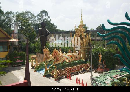 Statua di Buddha all'aperto all'ingresso del tunnel, la strada per la grotta Naga e molte statue Naga a Wat Maniwong. Foto Stock