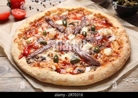 Gustosa pizza con acciughe e ingredienti su tavola in legno Foto Stock