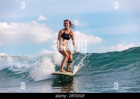 Donna surfista equitazione onda, â€ Changgu, Bali, Indonesia Foto Stock