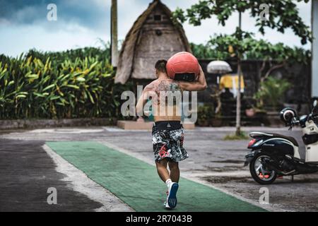 Uomo che si esercita con la palla medica, Canggu, Bali, Indonesia Foto Stock