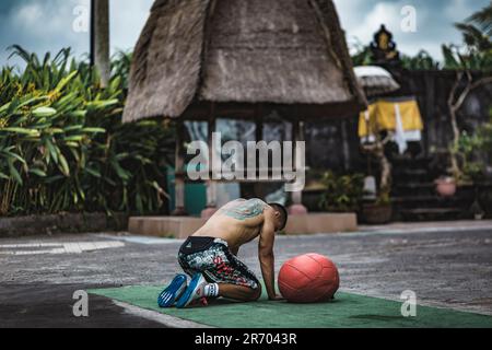 Uomo stanco dopo essersi allenato con la palla medica, Canggu, Bali, Indonesia Foto Stock