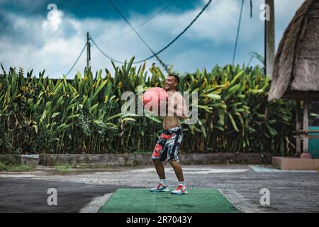 Uomo che si esercita con la palla medica, Â Canggu, Bali, Indonesia Foto Stock