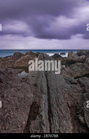 Formazione vulcanica sulla costa, con nuvole di pioggia scure sull'oceano Atlantico, Puerto de la Cruz, Tenerife, isole Canarie Foto Stock