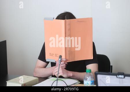 Amburgo, Germania. 12th giugno, 2023. Uno dei due imputati copre il suo volto mentre il processo di protezione dello Stato continua nel Palazzo di giustizia penale. L'accusa federale accusa un russo di 18 anni di Bremerhaven e un kosovaro tedesco di 16 anni di Iserlohn di sostenere lo "Stato islamico" (IS) tedesco o, nel caso del vecchio imputato, di aderire ALL'IS come membri. Secondo l'accusa, il più giovane convenuto ha previsto di effettuare un attacco in Germania a nome DELL'IS. Credit: Ulrich Perrey/dpa/Alamy Live News Foto Stock