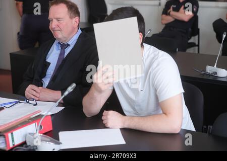 Amburgo, Germania. 12th giugno, 2023. Uno dei due imputati copre il suo volto accanto all'avvocato Thomas Domanski (l) mentre le procedure di protezione dello Stato continuano nel Palazzo di Giustizia penale. L'accusa federale accusa un russo di 18 anni di Bremerhaven e un kosovaro tedesco di 16 anni di Iserlohn di sostenere lo "Stato islamico" (IS) tedesco o, nel caso del vecchio imputato, di aderire ALL'IS come membri. Secondo l'accusa, il più giovane convenuto ha previsto di effettuare un attacco in Germania a nome DELL'IS. Credit: Ulrich Perrey/dpa/Alamy Live News Foto Stock