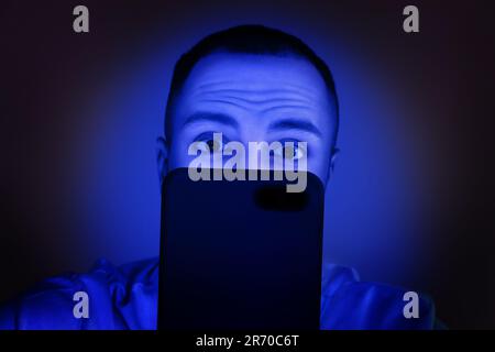 Dipendenza da Internet. Uomo che usa lo smartphone di notte. Di colore blu Foto Stock