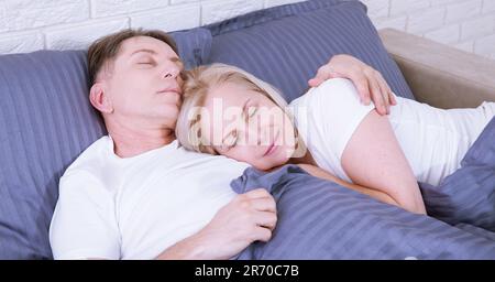 Calma coppia che dorme e si Spooning nel letto in camera da letto a casa. Foto Stock