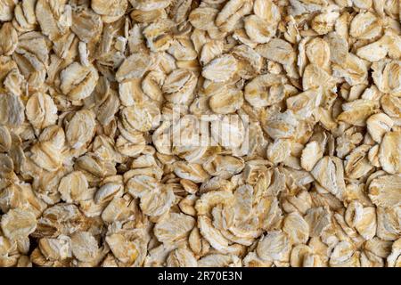 Versò una grande quantità di fiocchi di avena primo piano, sfondo di farina d'avena cruda cruda Foto Stock