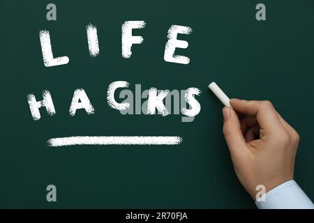L'uomo sottolinea le parole Life Hacks sulla lavagna verde, primo piano Foto Stock