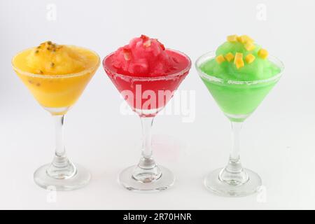 Tre deliziosi bicchieri martini pieni di cocktail dai colori diversi, tutti smerigliati con condensa isolati su sfondo bianco Foto Stock