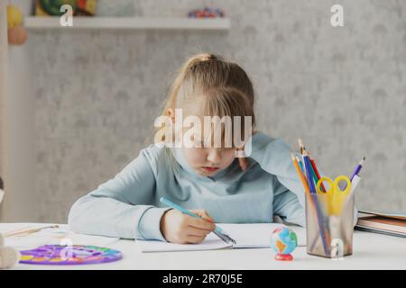 Scolaro esausto ragazza carina seduta alla scrivania, che soffre di fare i compiti a casa, stanco di studiare a casa, stressato con un compito difficile, preparandosi prima degli esami. Educazione domestica, homeschooling Foto Stock