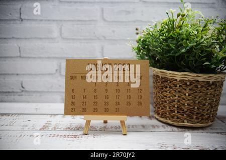 Agosto 2023 calendario mensile con decorazione a foglia verde su sfondo in legno Foto Stock