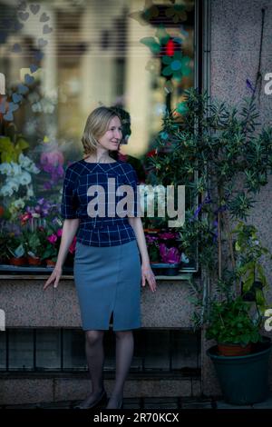 Una donna si trova sulla strada vicino alla finestra di un negozio di fiori. Portogallo. Foto Stock