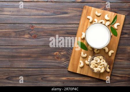 Latte vegano da anacardi in bottiglie su tavolo di legno, cibo alternativo vegetariano, concetto di consumo pulito. vista dall'alto con spazio di copia. Foto Stock