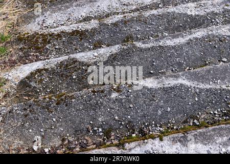 una vecchia scala in cemento rovinato e pietra nel parco, i dettagli delle vecchie parti della scala di cui sono danneggiati o distrutti Foto Stock