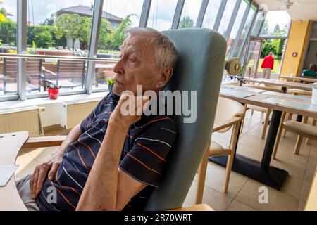 pensionato di vecchiaia seduto al tavolo di riposo a casa Foto Stock