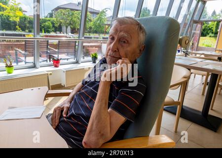 pensionato di vecchiaia seduto al tavolo di riposo a casa Foto Stock