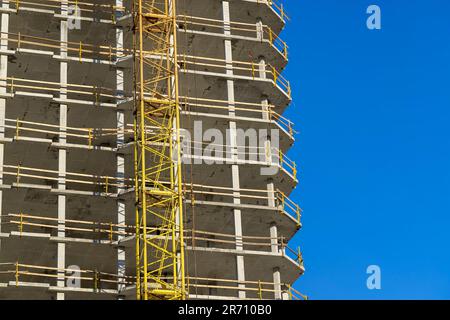 primo piano di una parte di un edificio residenziale a più piani in cemento e metallo, costruzione di un nuovo edificio a più piani con il sole Foto Stock