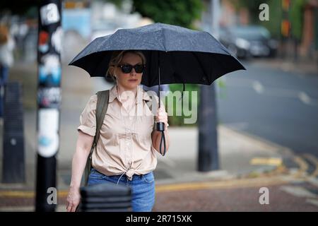 Londra, Regno Unito. 12th giugno, 2023. Una donna si rifugia sotto un ombrello durante una tempesta nel Queen's Park, nel nord di Londra. Diversi avvertimenti di tempesta sono in atto in tutte le parti del Regno Unito dopo un fine settimana di alte temperature. Photo credit: Ben Cawthra/Sipa USA Credit: Sipa USA/Alamy Live News Foto Stock