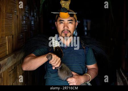 Ritratto di un giovane Nishi che indossa un tradizionale copricapo con il becco dell'uccello Hornbill e un coltello, Arunachal pradesh, India nord-orientale Foto Stock