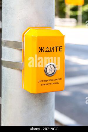 Segnale di attesa pedoni, utilizzato per aiutare le persone a attraversare la strada in modo sicuro. Testo in russo: ATTENDERE. Per attraversare la strada - premere il pulsante Foto Stock