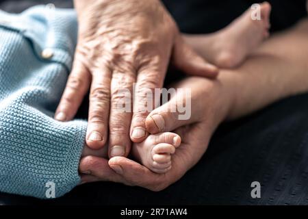 Piedi di un neonato nelle mani di una nonna, primo piano. Foto Stock