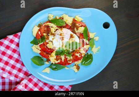 Deliziosa insalata caprese fatta in casa con un uovo in camicia Foto Stock