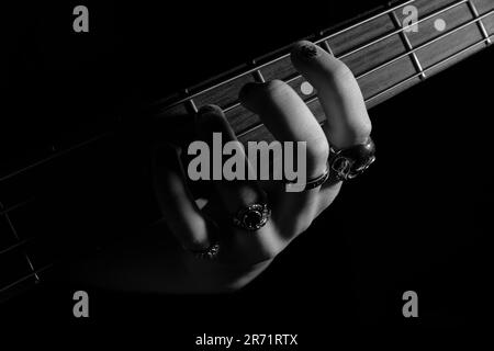 Una mano di donna con anelli suona una chitarra basso Foto Stock