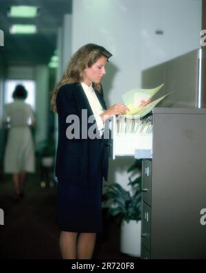 Uomini d'affari. Giovane donna. Executive. In piedi al file cabinet. Foto Stock