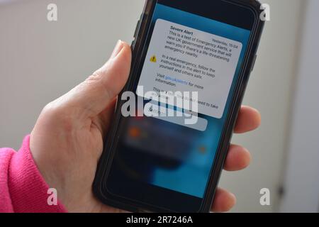 Cellulare in mano con schermo che mostra il testo ricevuto ieri, di prova per allarme grave, questo è un test di emergenza allarmi, un nuovo servizio governativo Foto Stock