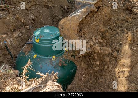 Un serbatoio di gas GPL è interrato con l'aiuto di un escavatore Foto Stock
