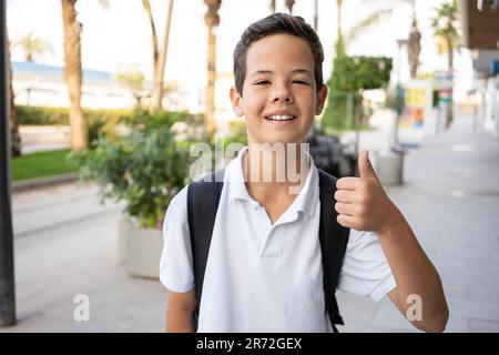 Una bella pre-teen boy fuori a scuola avente una buona volta Foto Stock