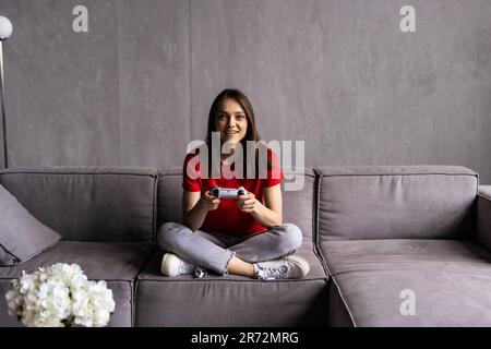 Giovane donna che gioca online arcade computer, divertirsi durante il blocco covid Foto Stock