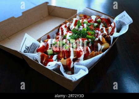 Una scatola di cartone riempita con patatine fritte con ketchup e maionese Foto Stock