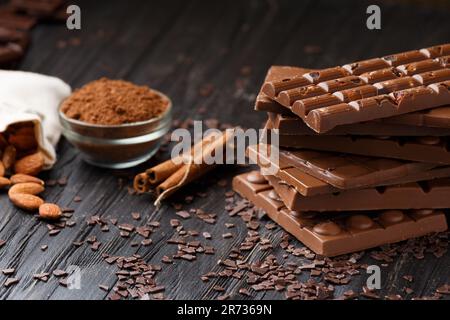 Cioccolato fatto a mano con nocciole, pezzi di cioccolato fondente, cacao su uno sfondo di legno scuro vista dall'alto. Concetto di varietà di cioccolato. Foto Stock