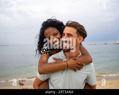 Coppia eterosessuale multietnica innamorata sulla spiaggia. Luna di miele, coppia che si diverte Foto Stock