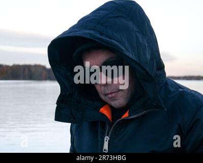 Ritratto dell'uomo che indossa abiti caldi mentre si trova contro il lago durante l'inverno Foto Stock
