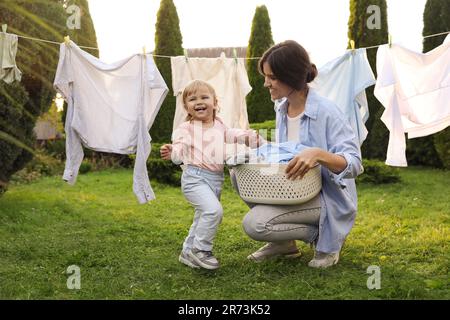 Madre e figlia vicino linea di lavaggio con vestiti asciuganti in cortile Foto Stock