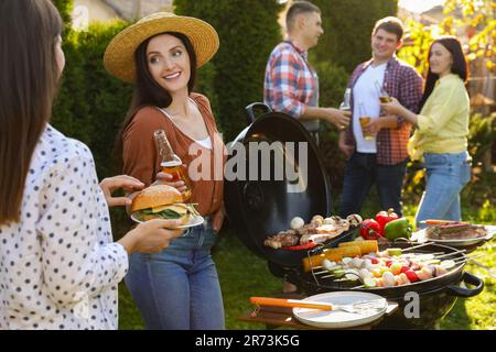 Gruppo di amici che hanno barbecue partito all'aperto Foto Stock