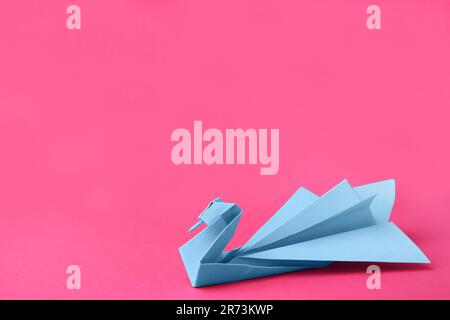 Carta blu chiaro cigno su sfondo rosa, spazio per il testo. Origami arte Foto Stock