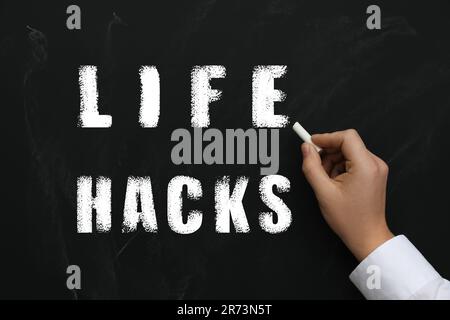 L'uomo che scrive parole Life Hacks con gesso su lavagna, primo piano Foto Stock