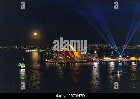 VIVID Sydney 2023. Illuminazione delle vele, Sydney Harbour. Luna che sorge sopra il Teatro dell'Opera. John Olsen ha animato le opere d'arte. Vista dal ponte Foto Stock