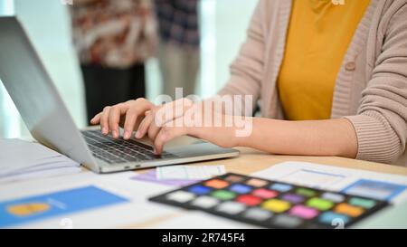 Immagine ravvicinata di una designer di grafica professionale asiatica o di un'interfaccia utente, lo sviluppatore UX sta lavorando sul suo computer portatile alla sua scrivania in ufficio. Foto Stock