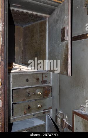 Una vecchia cassaforte in metallo arrugginito d'epoca con una porta aperta. I fogli sono nella cassaforte. Antico ufficio sicuro per la conservazione dei documenti Foto Stock